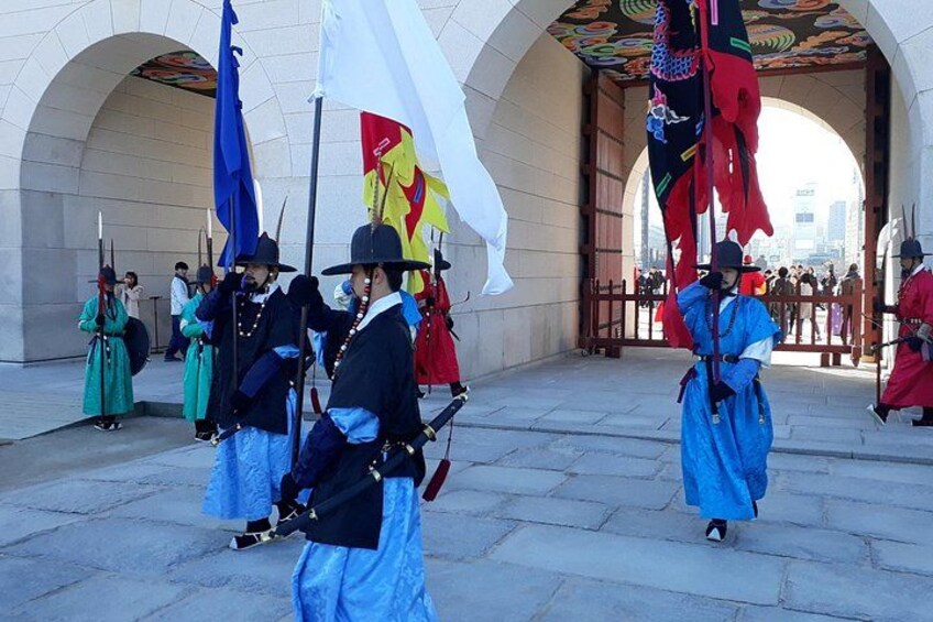 Eine historische Nachstellung mit Teilnehmern in traditioneller Tracht und Fahnen in einer Stadt. 2