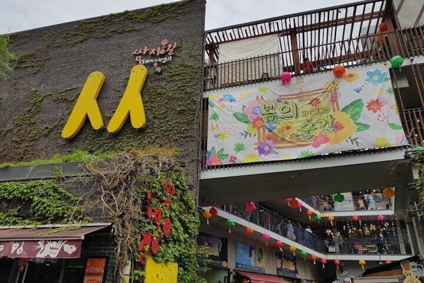 Un edificio con un letrero amarillo grande, un banderín con texto coreano y un balcón decorado con faroles de colores. 4