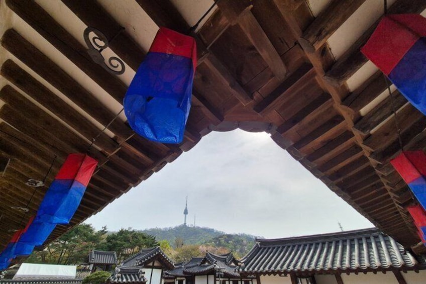 Un tejado coreano tradicional con adornos azules y rojos, una pagoda y una montaña al fondo. 3