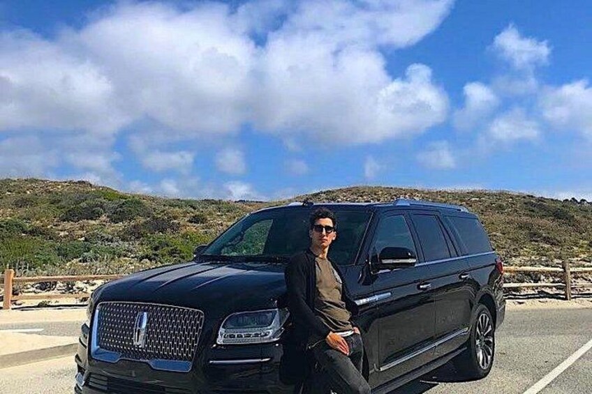 Un SUV nero parcheggiato su una strada con un paesaggio collinare sullo sfondo. 2