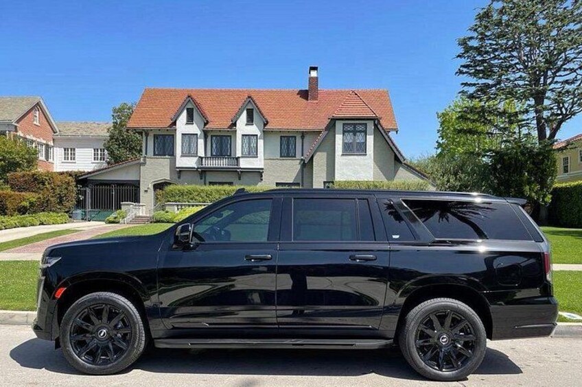 Un SUV nero parcheggiato su una strada, con una grande casa sullo sfondo. 5