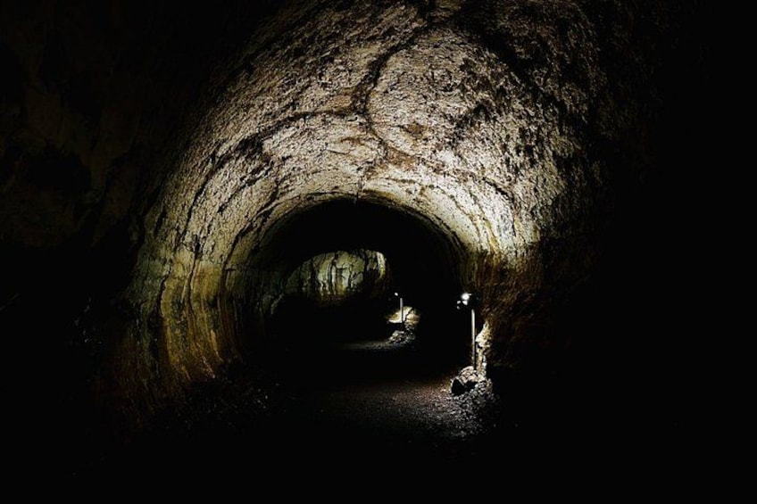 En mørk tunnel med ru stenvægge og en lyskilde i enden. 3