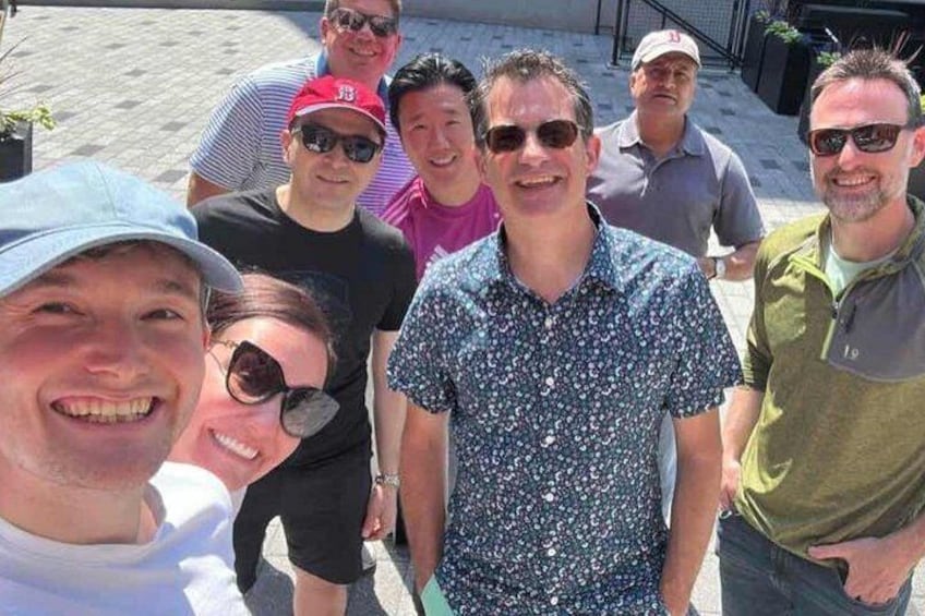 A group of people standing outdoors, possibly on a sidewalk or patio area. 4