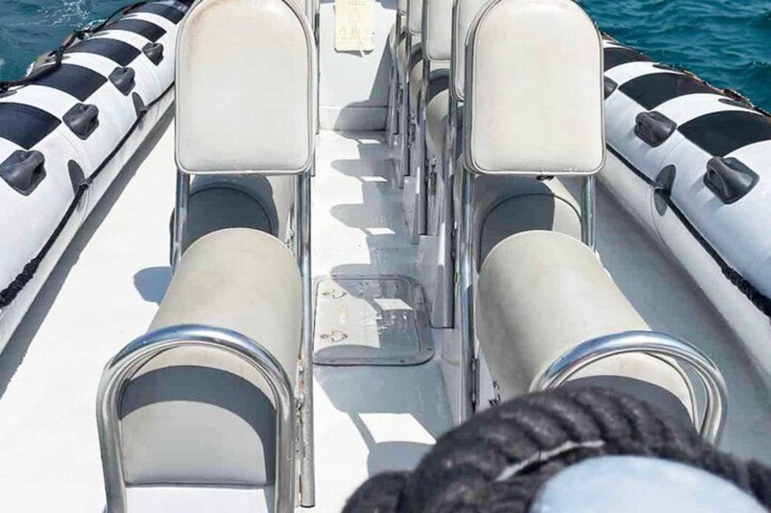 A boat's seating area with cushioned chairs and a rope. 4