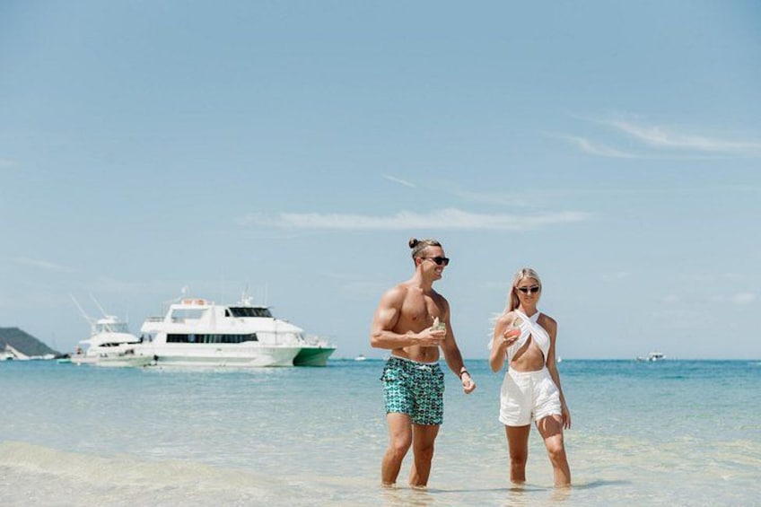 Dos personas de pie en una playa, con un bote al fondo. 4