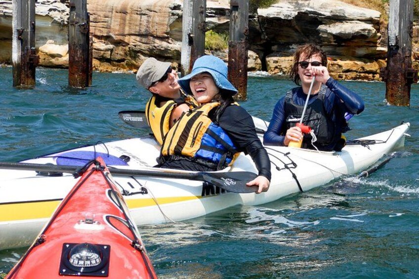 A white kayak with three people wearing life jackets, a red kayak, and rocky cliffs in the background. 2