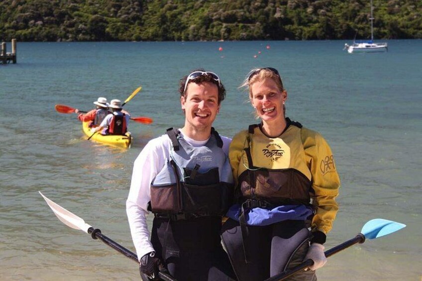 Two people standing by a lake with kayaks in the background. 4