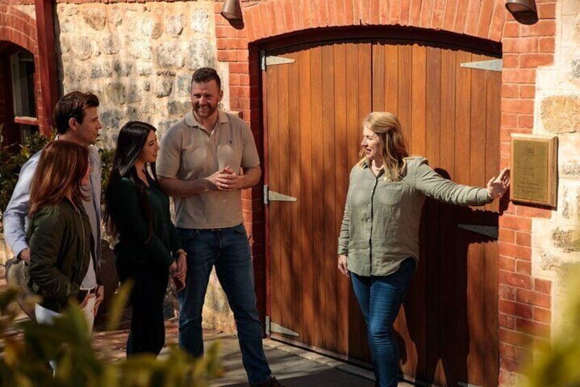 A group of people standing in front of a wooden door with a stone wall and a plaque. 2