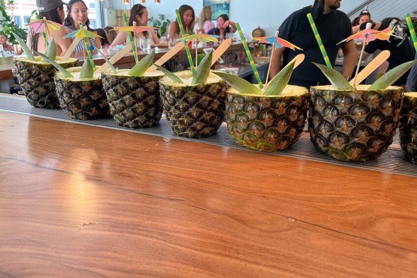 A row of decorated pineapples on a wooden counter in a public space. 5