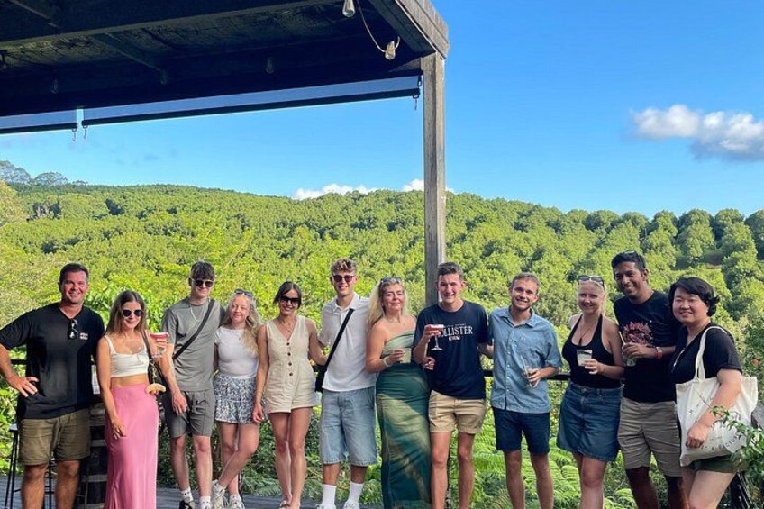 A group of people standing under a shelter with a lush green landscape in the background. 3
