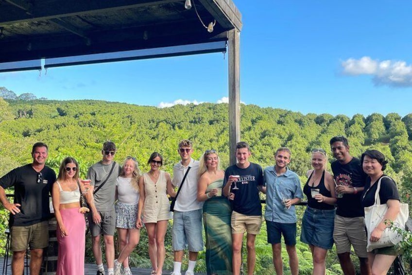 A group of people standing under a shelter with a mountainous landscape in the background. 2
