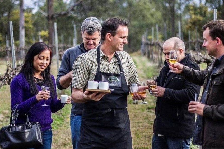 A group of people tasting wine outdoors, surrounded by trees. 4