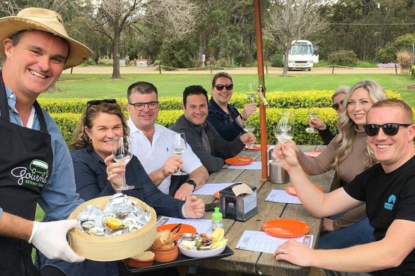 A group of people toasting at an outdoor table with food and drinks. 5
