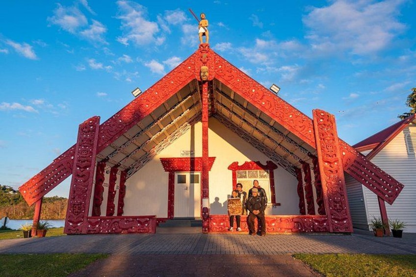A red-roofed building with a white facade, two people standing in front, and a clear blue sky. 1
