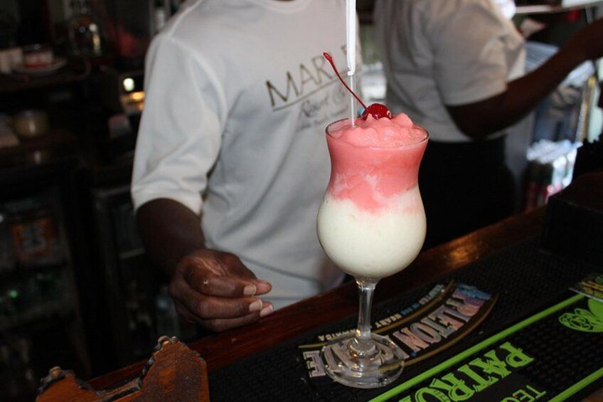 A bartender in a white shirt behind a bar counter with a drink in a glass. 5