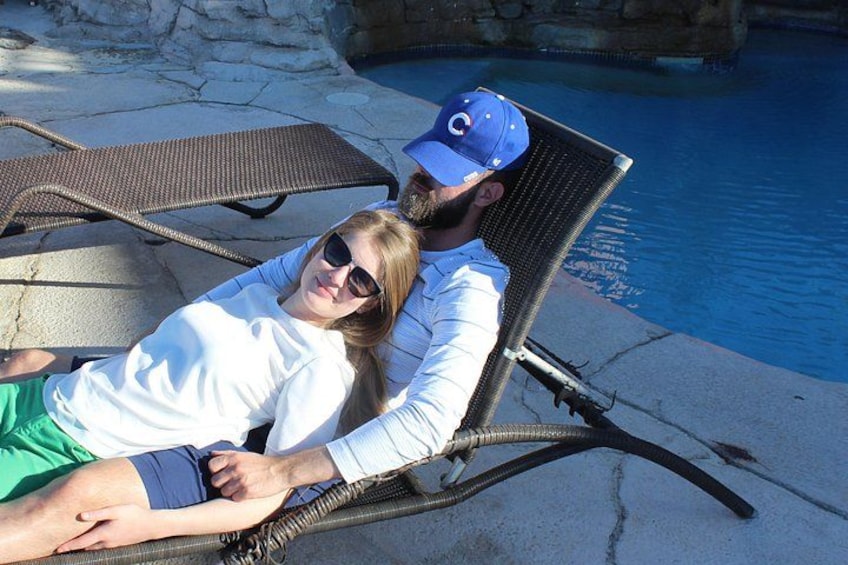 Two people relaxing by a poolside lounge chair. 2