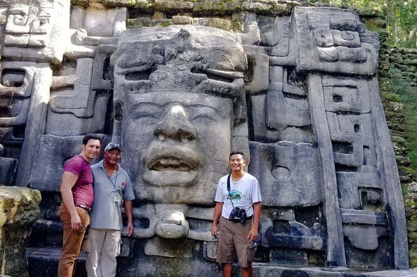A large stone carving with intricate designs and a face, surrounded by smaller carvings. 5