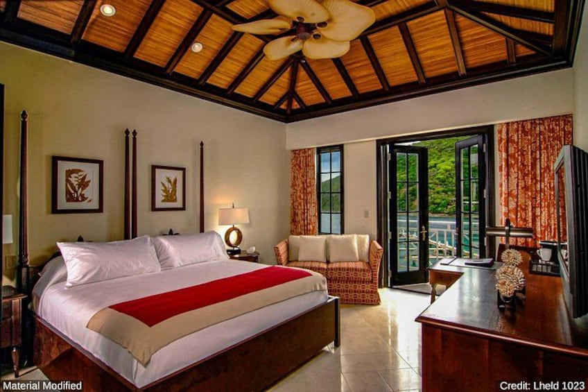 A bedroom with a large bed, a desk, and a balcony. 2