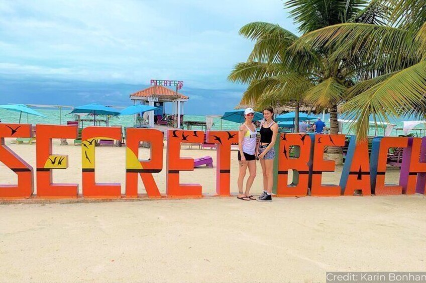 A beach with large letters spelling "SECRET BEACH" and a lifeguard tower in the background. 5