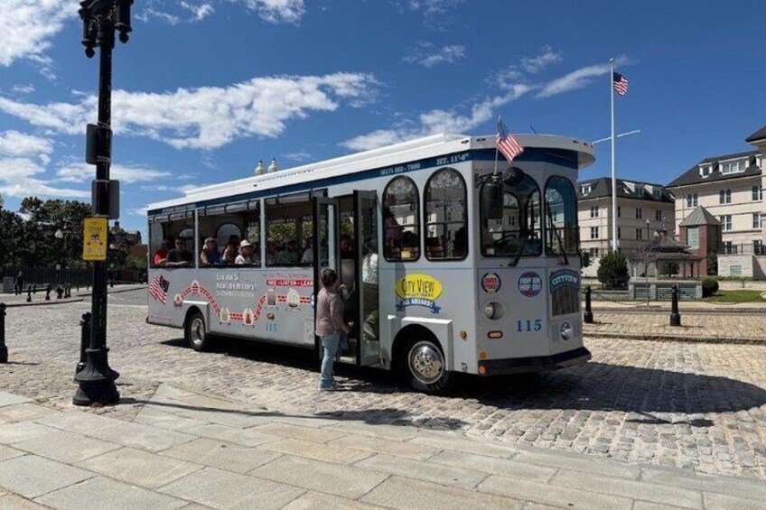 A city bus with an American flag, parked on a cobblestone street with a pedestrian crossing nearby. 4