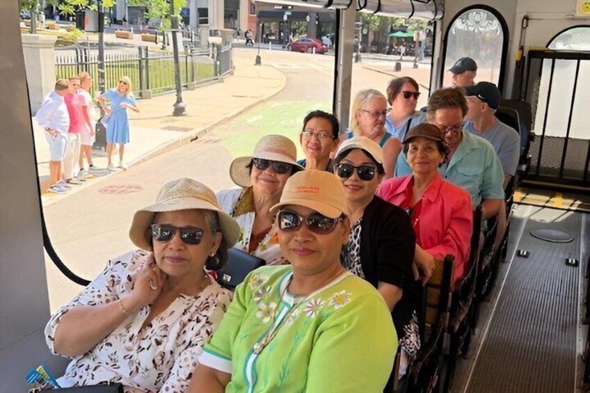 A group of people on a bus, with a street and buildings visible through the windows. 2