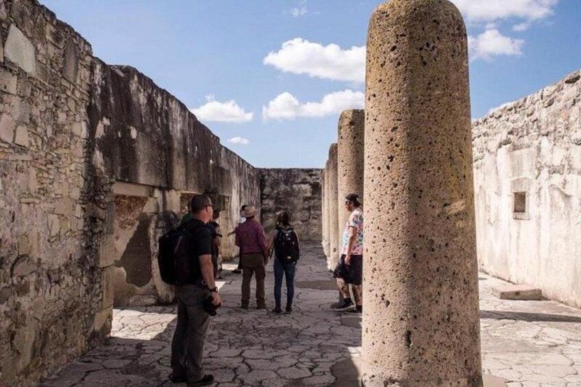 A historical site with stone columns and walls, visitors walking along a pathway. 5
