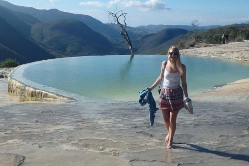A person walking near a body of water with mountains in the background. 1
