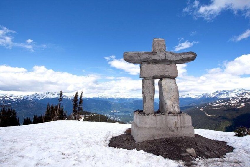 A stone totem on a snowy hill with a mountain range in the background. 1