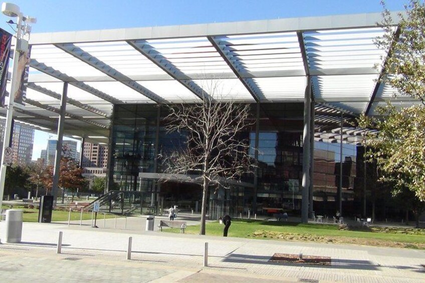 A modern building with a glass facade and a metal roof structure. 1