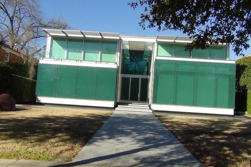 A modern building with a glass facade and a concrete pathway leading to the entrance. 4