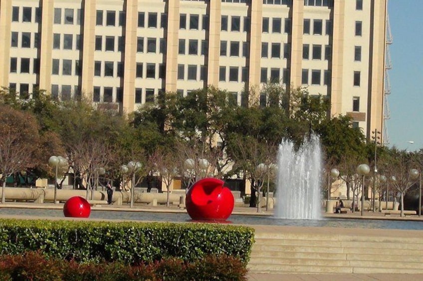 A fountain, red spherical sculptures, and a building in the background. 2