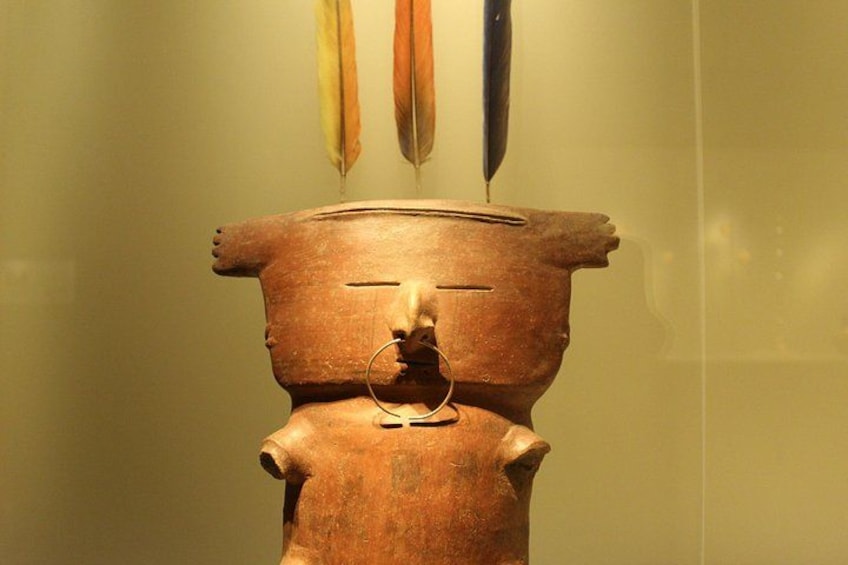 A terracotta sculpture with a human-like face and a bird perched on top. 1