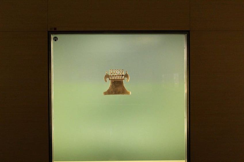 A framed object with a golden color and a design that includes a crown and a figure. 3