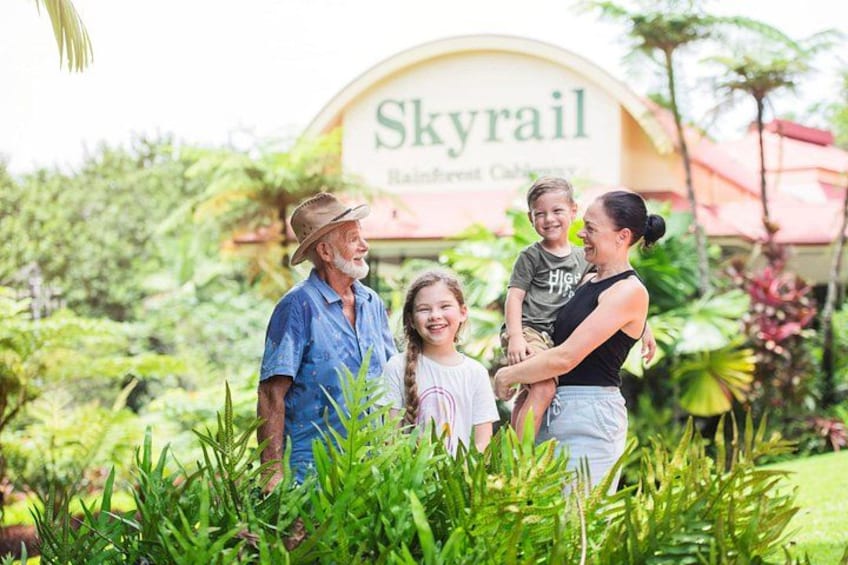 A family standing in front of a sign that reads 'Skyrail Rainforest Cabana.' 4