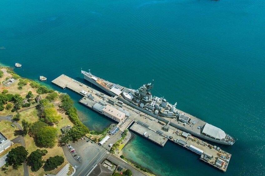 An aircraft carrier docked at a pier with a clear blue sea in the background. 5