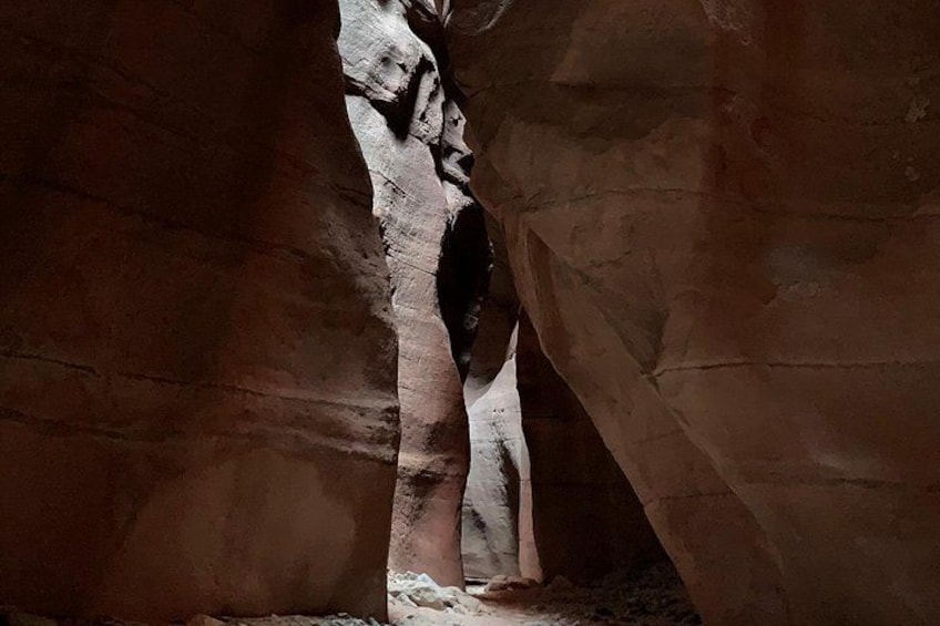A person standing in a narrow cave passage with rock walls. 2