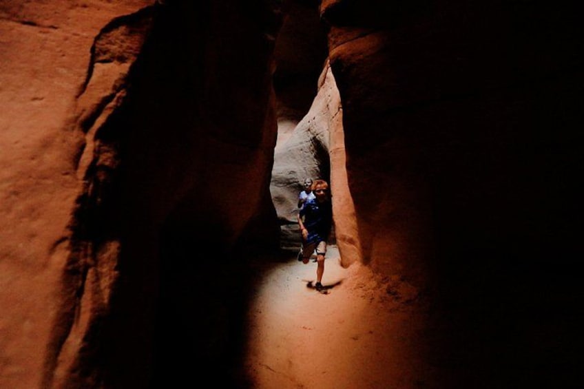 A person standing in a narrow canyon with reddish rock walls. 3