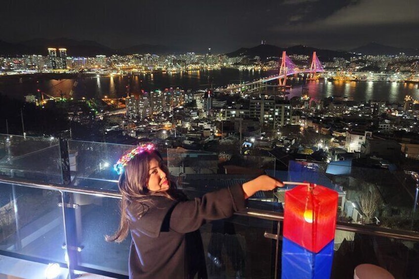 A person overlooking a cityscape at night with a bridge in the background. 1
