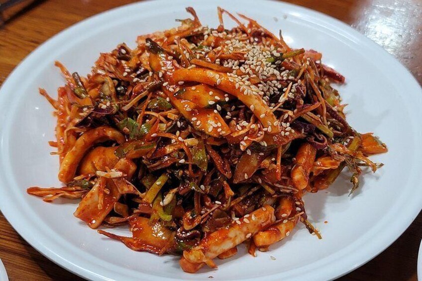 A plate of spicy stir-fried vegetables and meat garnished with sesame seeds. 2