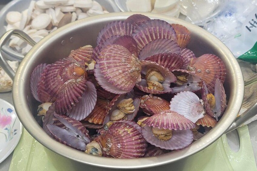A bowl of scallops with their shells, some open and some closed, on a table. 5