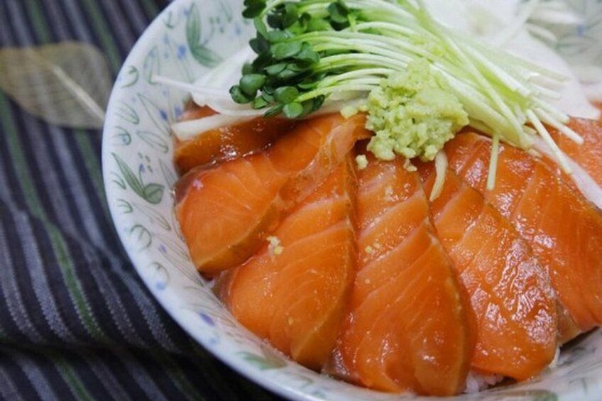 A bowl of sliced salmon with garnishes. 3