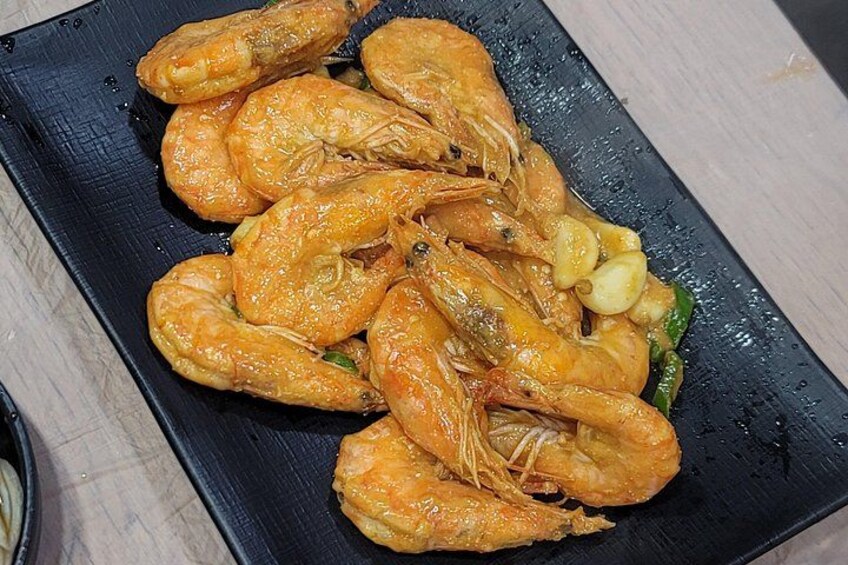 A black plate with cooked shrimp and some vegetables. 4