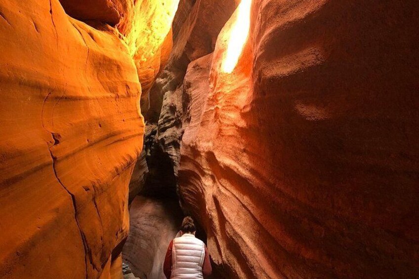 A person walking through a narrow canyon with reddish rock walls. 5