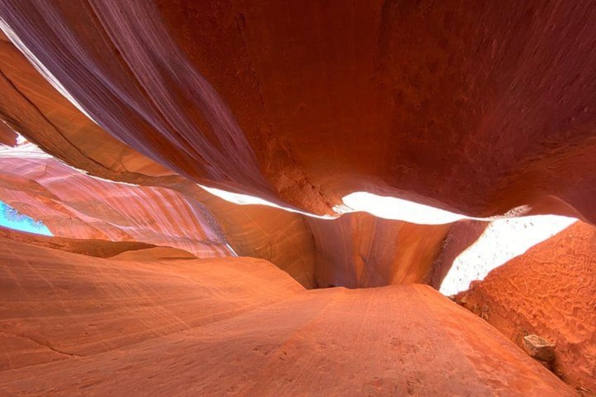 A narrow canyon with smooth, reddish rock walls and a narrow opening. 4