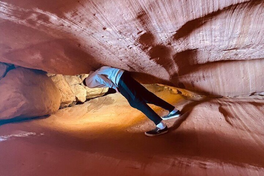 A person walking through a narrow canyon with reddish rock walls. 4