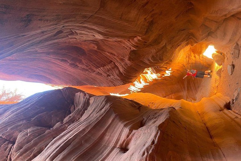 A person inside a canyon with red rock walls and a narrow passageway. 2