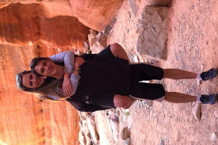 Two people standing in a canyon with red rock formations. 4