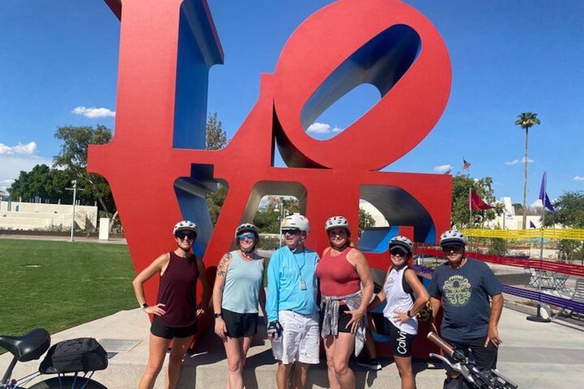 A group of people posing in front of a large red sculpture with a blue outline. 2