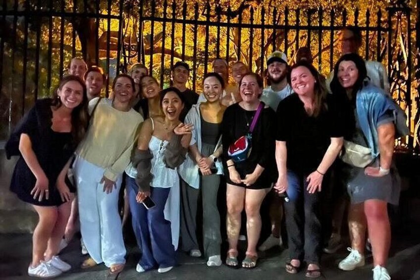 A group of people posing in front of a decorative fence with golden patterns. 2