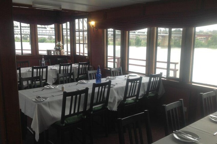 Ein Restaurant mit gedeckten Tischen, großen Fenstern und Blick auf ein Gewässer. 3